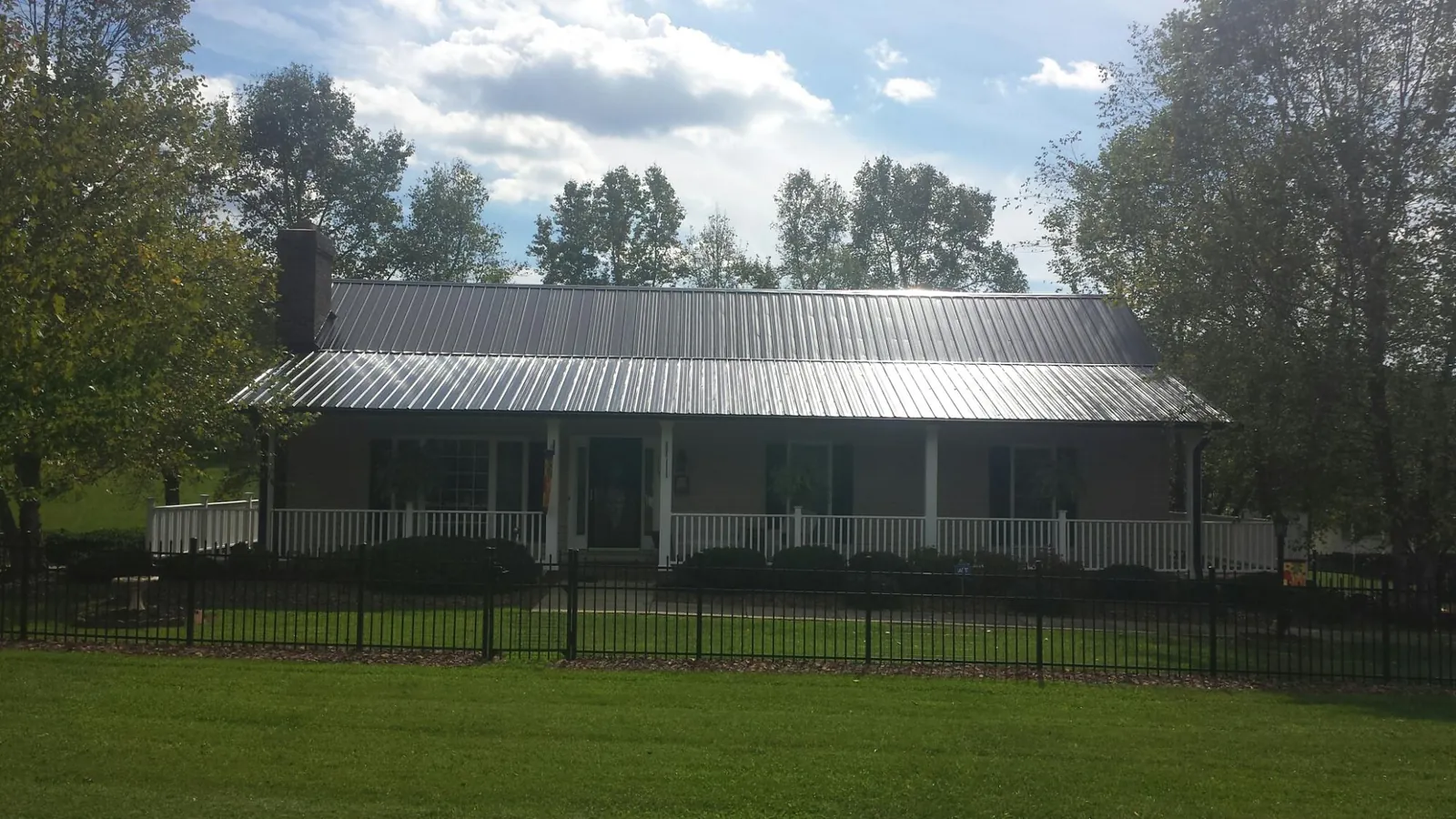 Gray metal roof on a brick ranch with a full width front porch — Gutter Guard Installation work by our crew in New Berlin