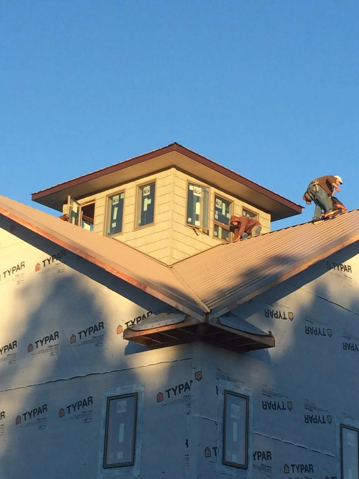 Roofers working around a rooftop cupola on a new metal roof at sunset — Roof Waterproofing in New Berlin by Roofing Brothers